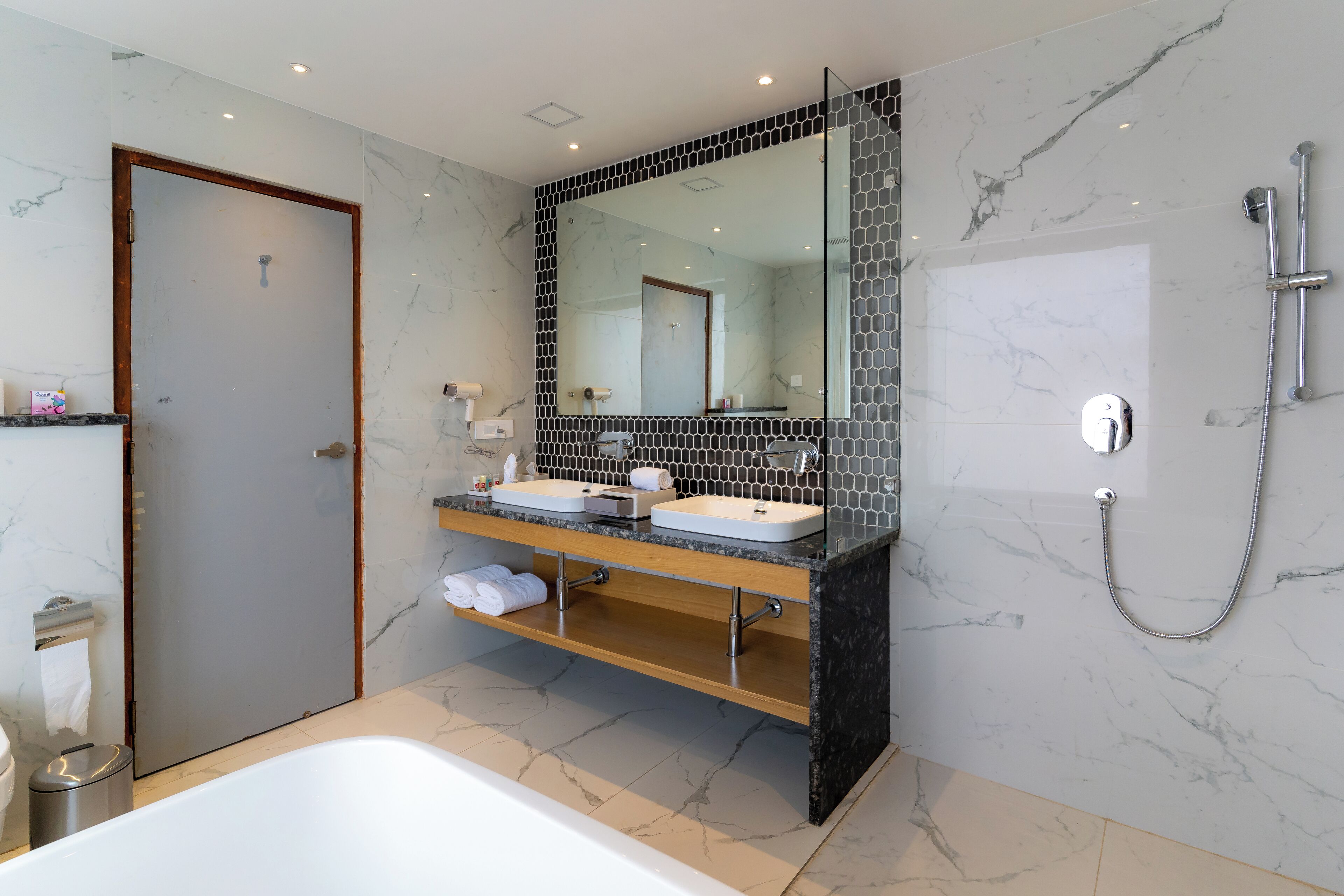 A modern bathroom with a double sink vanity, a large mirror, and a separate shower area.