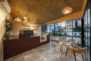 A modern reception area with a wooden reception desk, wicker chairs, and pendant lighting.