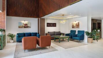 Una sala moderna con sofás azules, un sillón marrón y una mesa de centro verde.