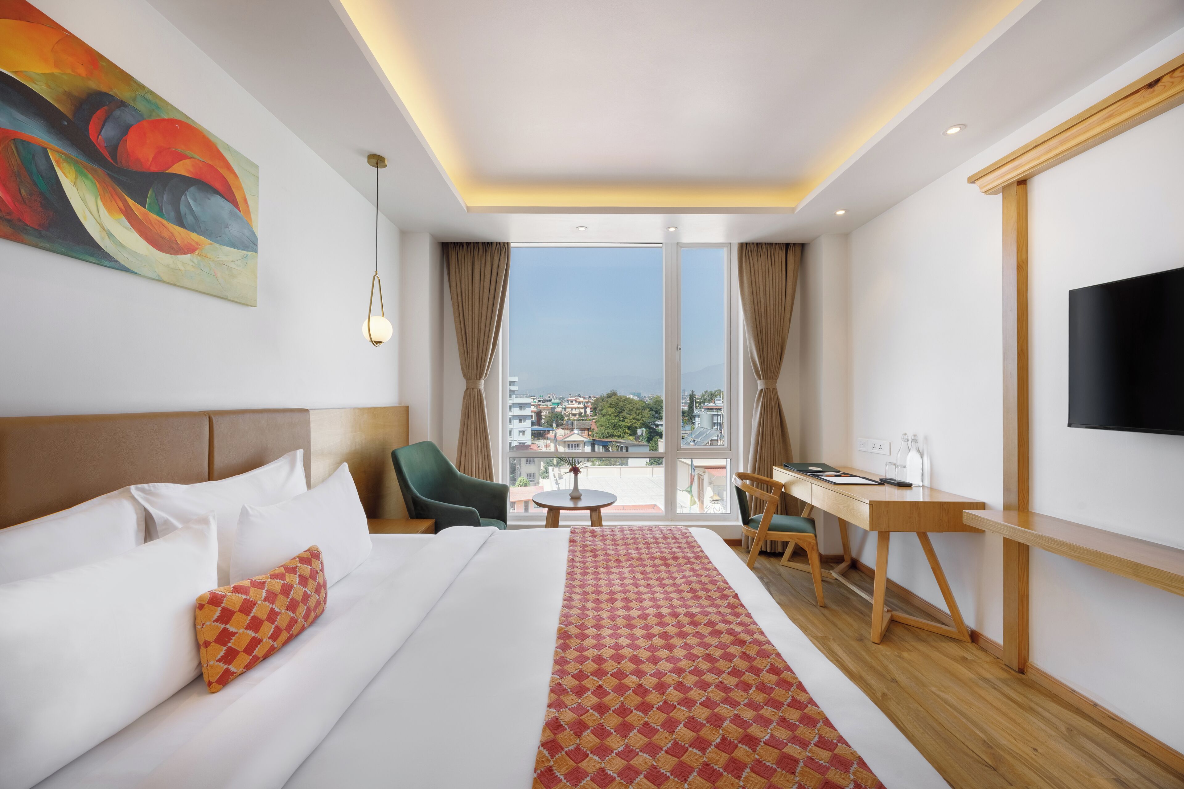 A hotel room with a large bed, a desk, a chair, a TV, and a painting on the wall.