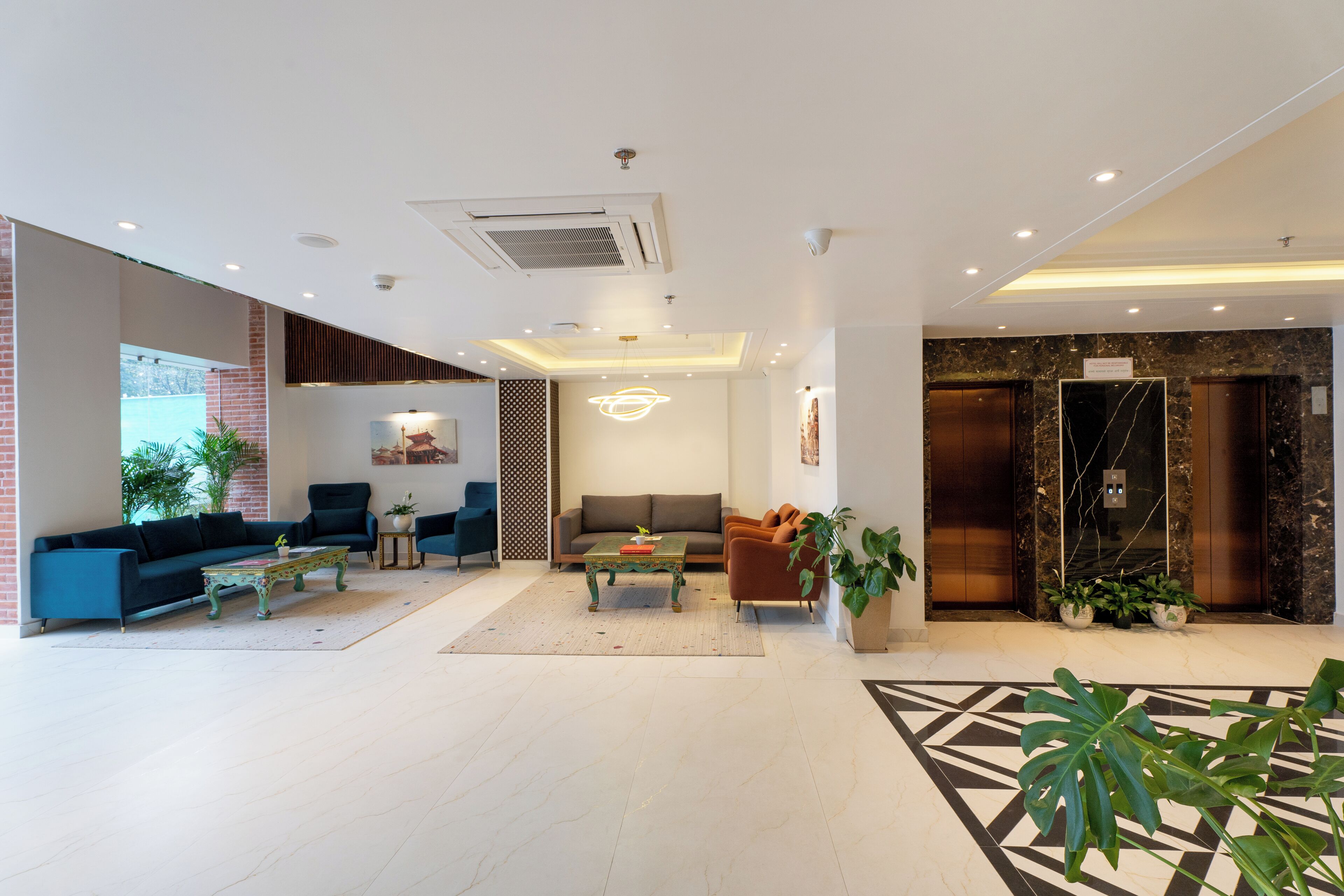A modern lobby with a sofa, armchairs, a coffee table, and potted plants.