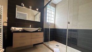 A modern bathroom with a large sink, a mirror, a glass shower enclosure, and a window. - PEL1900 (Cannes)
