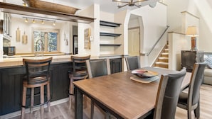 A modern kitchen with a wooden island, bar stools, and a dining table with chairs. - Just Steps from Resort Shuttle & Great Amenities like Shared Pool & Hot Tubs (Keystone)
