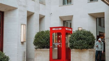 Ein modernes Gebäude mit einer roten Telefonzelle, einer Treppe und einer Person, die am Eingang steht.