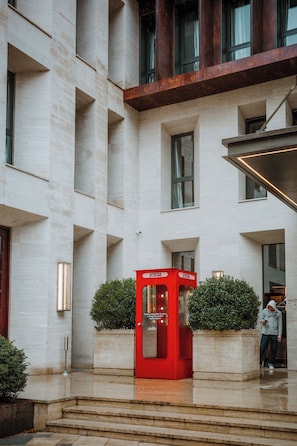 Een modern gebouw met een rode telefooncel, een trap en een persoon die bij de ingang staat.