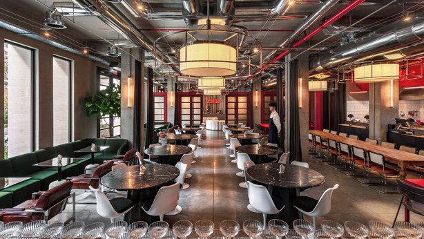 A modern restaurant interior with round tables, green and white chairs, and a central walkway. - Hotel Afisha (Tbilisi)