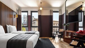A hotel room with two beds, a desk with a telephone, a chair, and a television. - Hotel Afisha (Tbilisi)