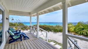 A wooden deck with two Adirondack chairs overlooking a beach. - New Luxury Beachfront Bungalows w/Heated Pool, Pink-Sand Beach (Governors Harbour)