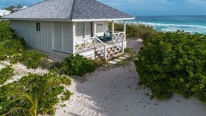 A beach house with a covered porch, a small deck, and a view of the ocean. - New Luxury Beachfront Bungalows w/Heated Pool, Pink-Sand Beach (Governors Harbour)