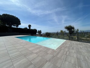 Une piscine rectangulaire à l’eau bleu clair, entourée d’une terrasse carrelée.