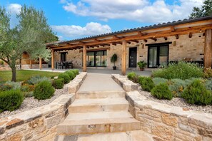 A stone building with a wooden pergola, outdoor seating, and a stone pathway leading to the entrance. - Holiday House La Gronda (Rovinj)