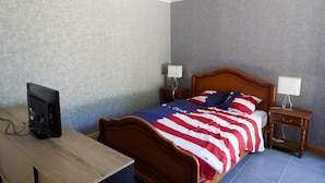 Una camera da letto con un letto, una scrivania con un computer e due comodini con lampade.
