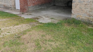 Un edificio con facciata in mattoni, pavimento in cemento e porta del garage socchiusa.
