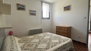 A bedroom with a bed, a dresser, and two paintings on the wall.