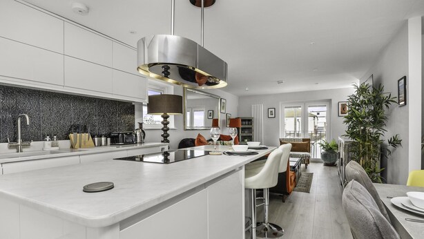 A modern kitchen with a central island, white cabinetry, and a large pendant light. - Sunset Townhouse With Free Parking (Brighton)