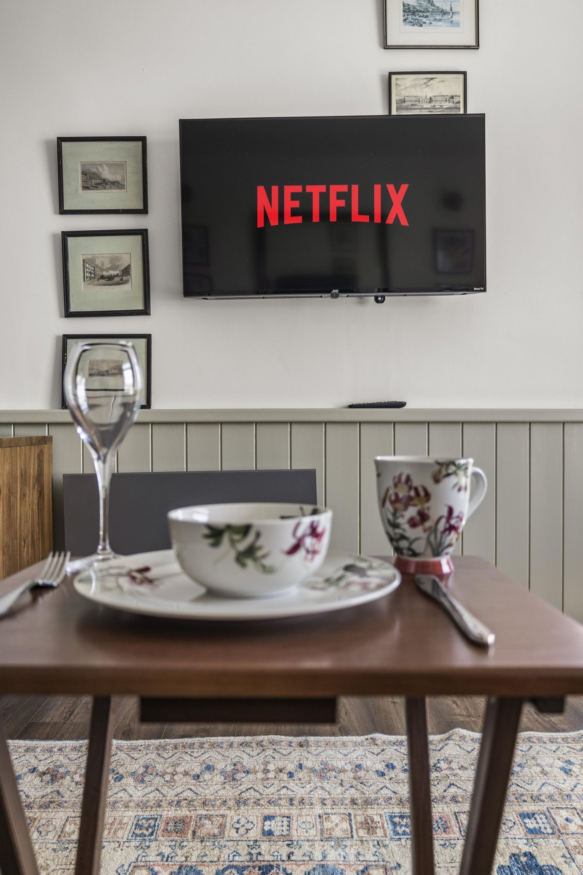 A dining table with a bowl and a cup, a wine glass, and a framed picture on the wall.