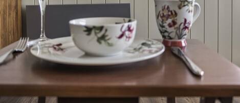 A dining table with a bowl and a cup, a wine glass, and a framed picture on the wall.