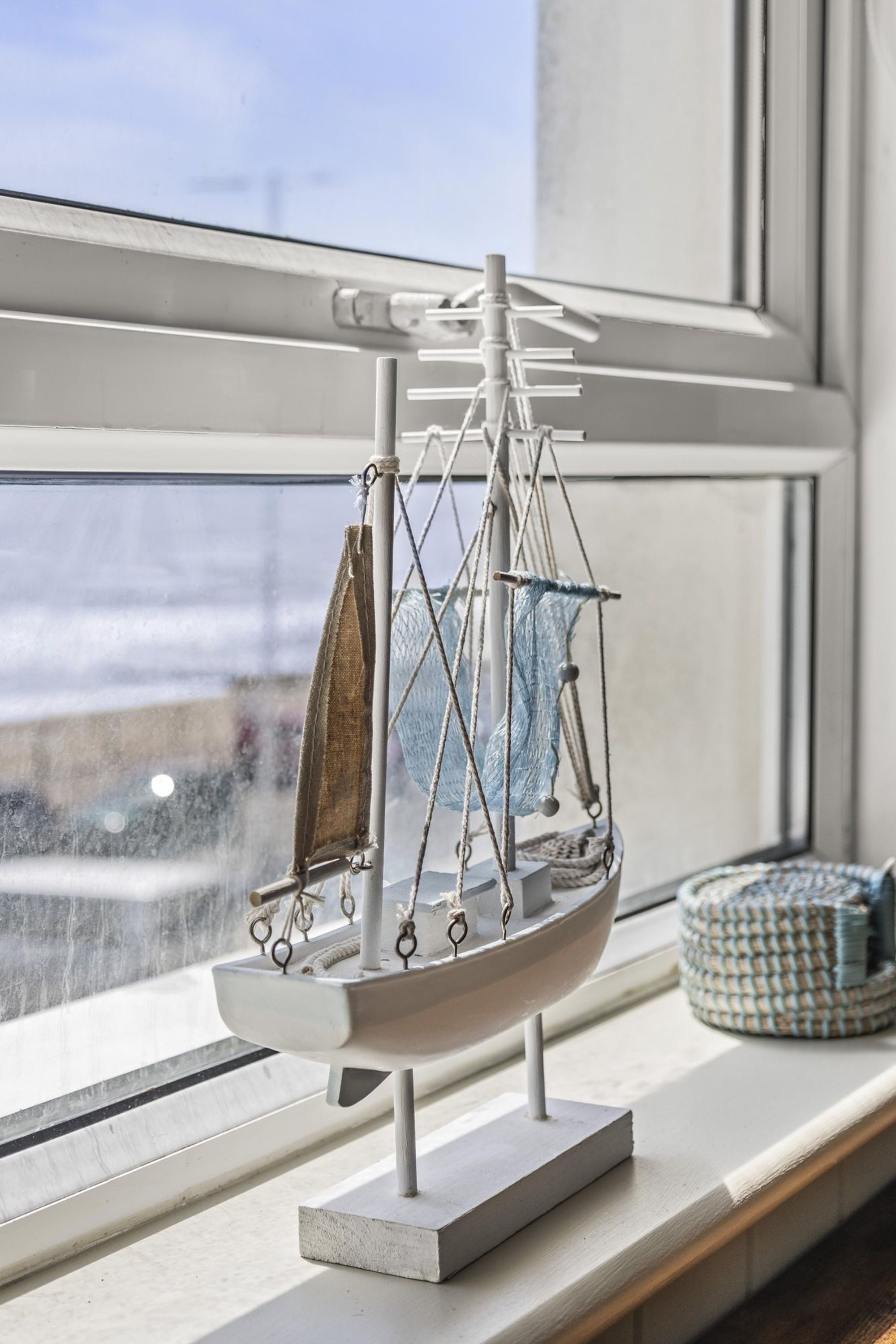 A model sailboat on a stand by a window.
