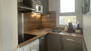 Une cuisine compacte équipée d’un four à micro-ondes, d’une cuisinière et d’un lave-linge intégrés.