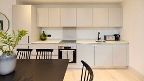 Une cuisine moderne avec des meubles blancs, un plan de travail noir et un coin repas comprenant une table et des chaises.