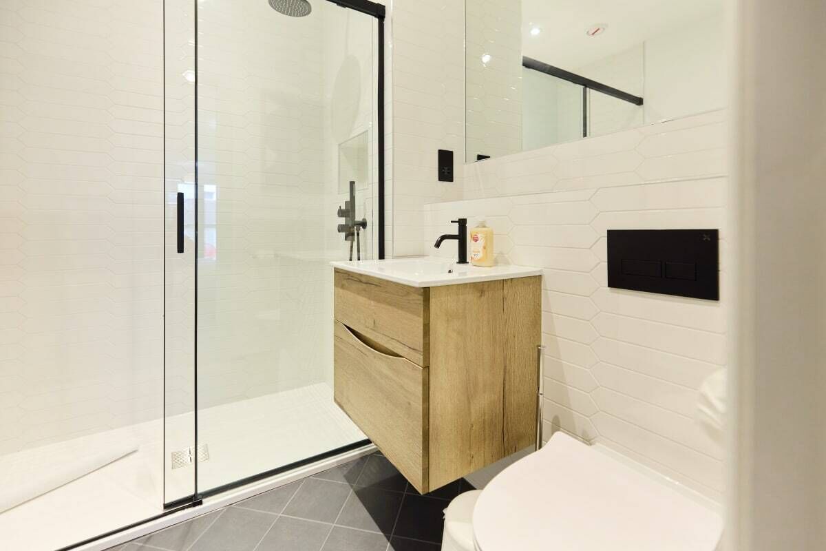 A modern bathroom with a glass shower enclosure, a wooden vanity, and a white toilet.