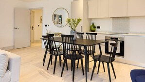 Une cuisine moderne avec des meubles blancs, une table à manger avec des chaises noires et un vase rempli de fleurs.