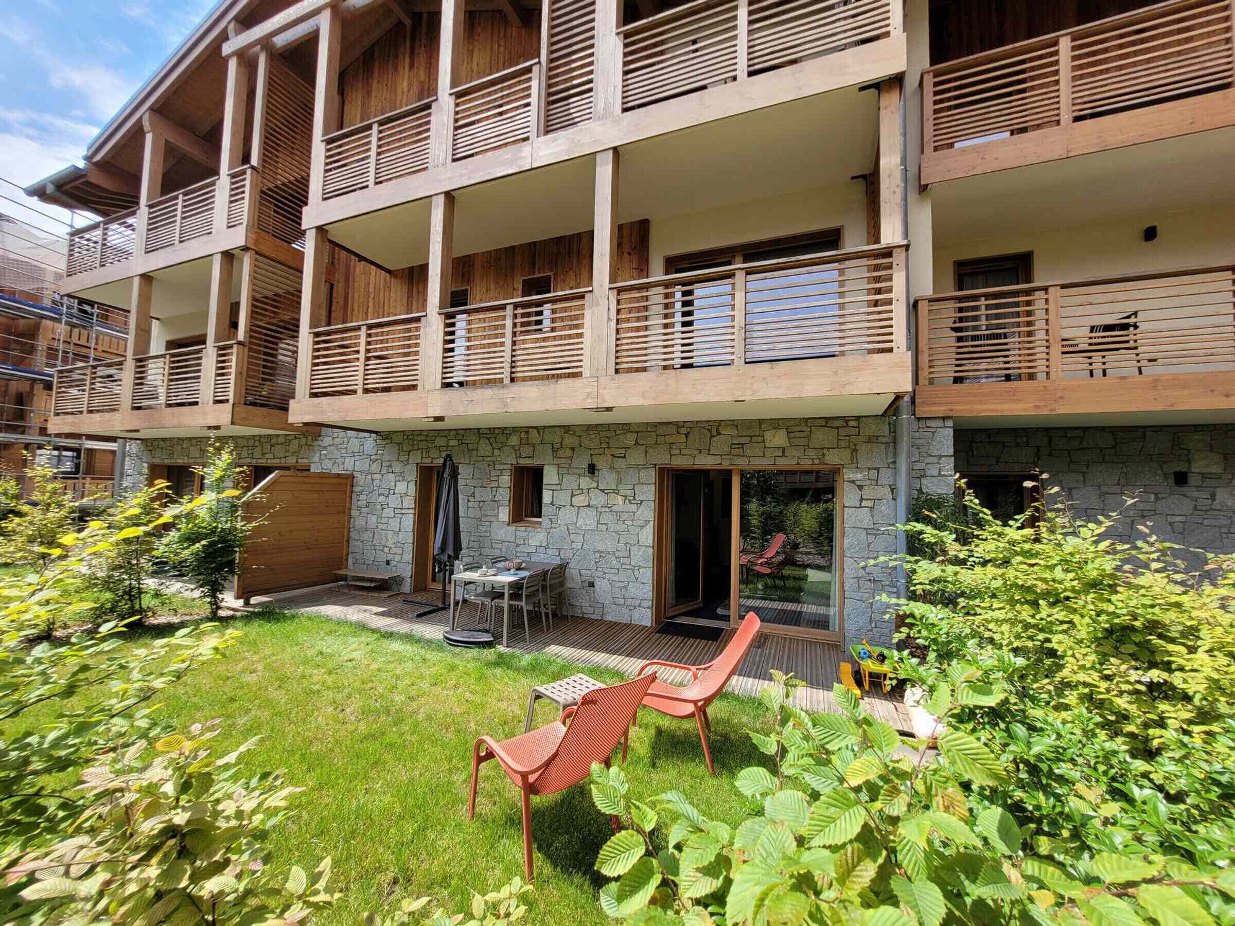 A multi-story building with balconies, a stone facade, and a small outdoor seating area with a table and chairs.