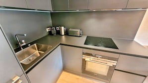 Una cocina moderna con un lavamanos de acero inoxidable, horno empotrado, hornilla y tostadora.