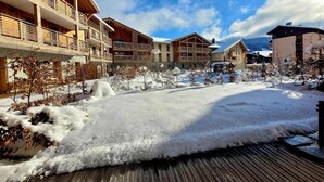 Un patio cubierto de nieve con edificios de madera, balcones y cielo despejado.