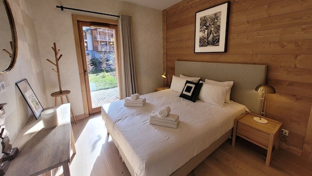 Un dormitorio con una cama grande, cabecera de madera, mesita de noche con lámpara y un cuadro enmarcado en la pared.