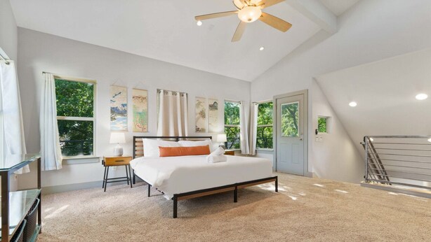 A bedroom with a bed, a desk, a chair, a ceiling fan, and large windows. - 2915 E 14th xxxxxxxx (Austin)