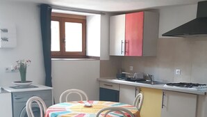 Un espace de vie compact comprenant un coin repas, une kitchenette et un canapé avec des coussins.