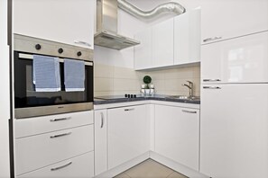 A modern kitchen with white cabinetry, a stainless steel oven, and a built-in range hood.