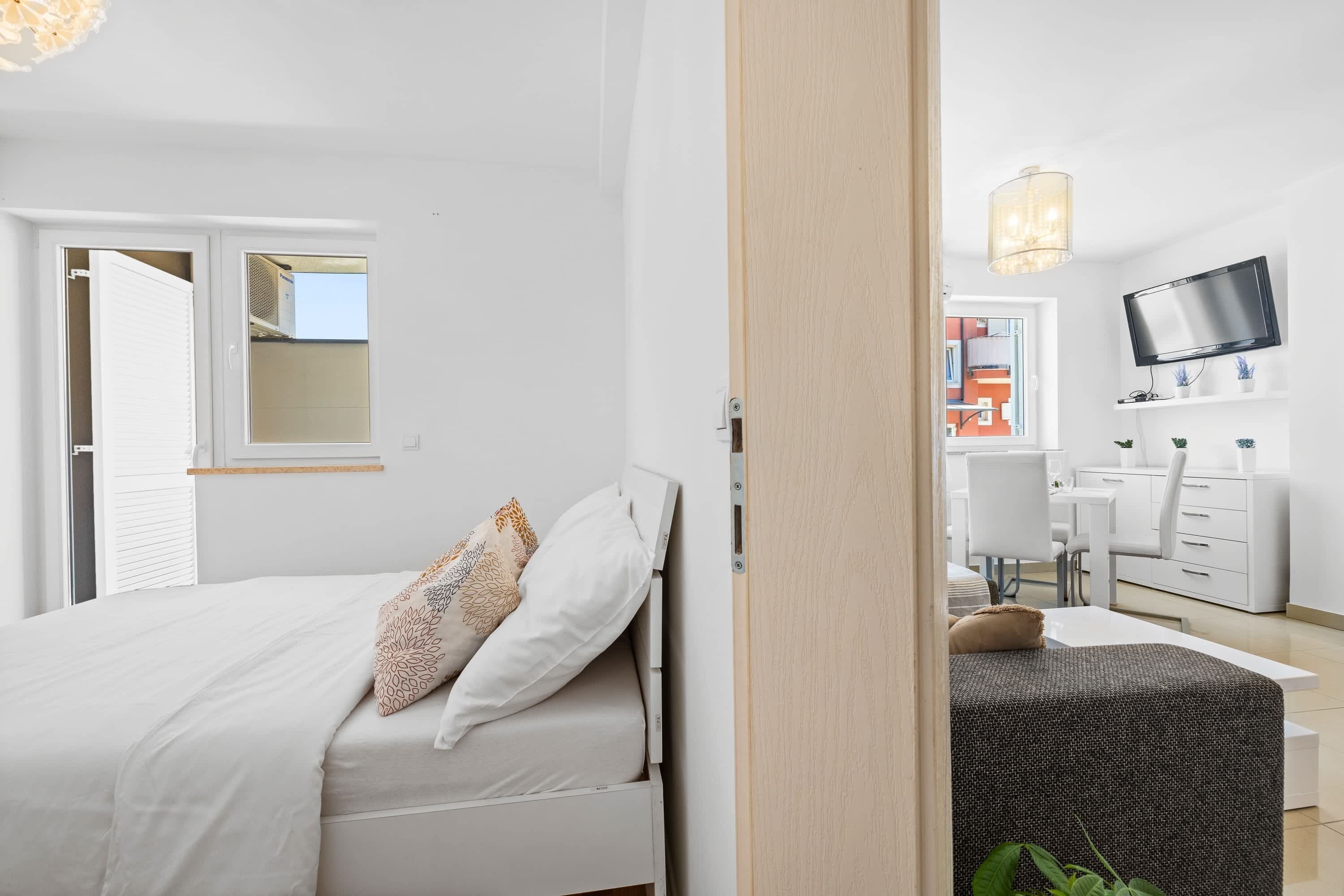 A bedroom with a bed, a desk, a chair, and a TV.