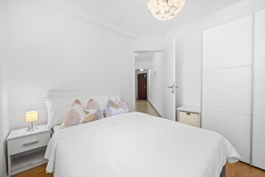 A modern bedroom with a bed, nightstand, lamp, and wardrobe.