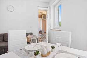 A dining area with a table set for two, a sofa, and a view of the outdoors.