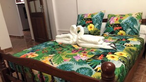 Una cama con colcha floral, un par de toallas blancas y un cabecero de madera.