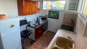 Cocina compacta con refrigerador, microondas, lavaplatos y armarios de madera.