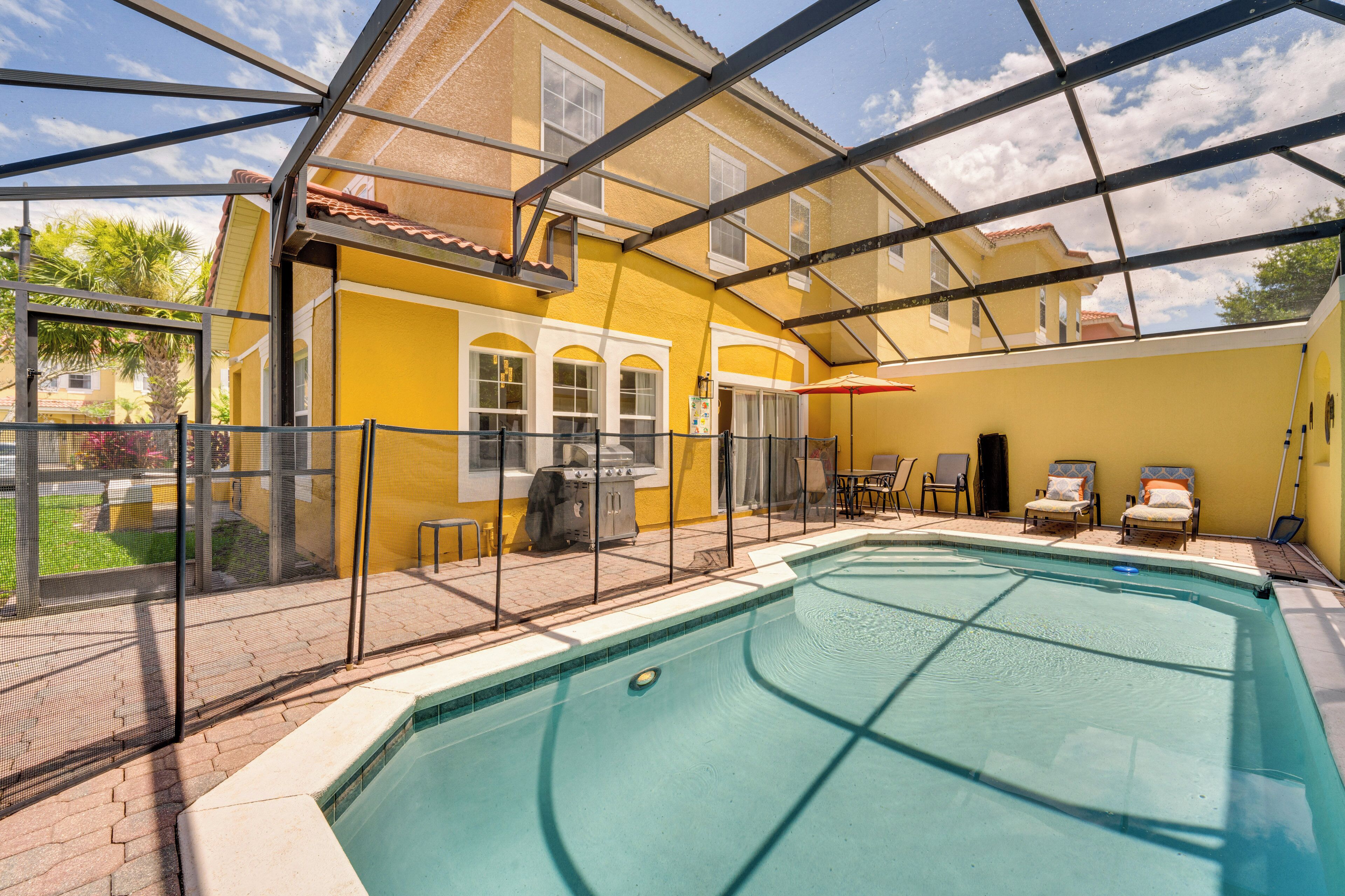 A swimming pool with a covered patio area, a grill, and outdoor seating.