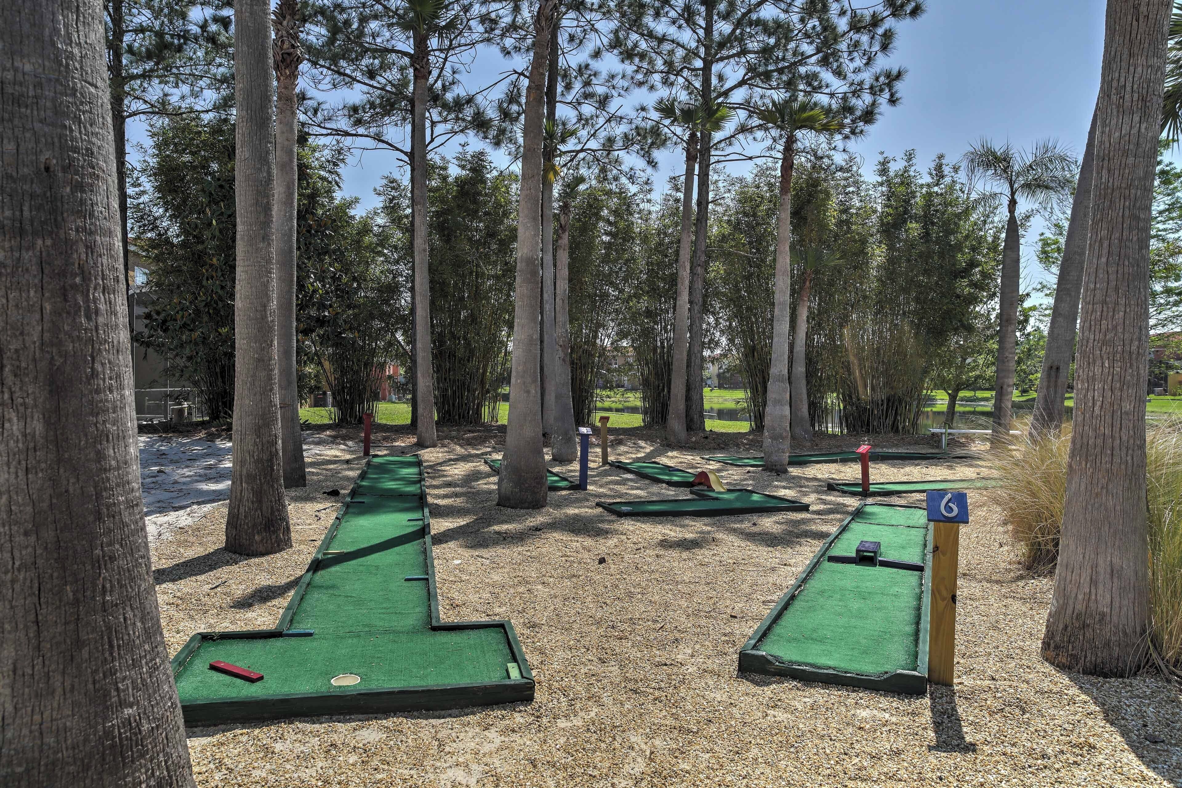 Un campo de minigolf con hoyos numerados, rodeado de árboles altos.