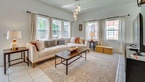 A living room with a sofa, coffee table, lamp, and a television.