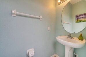 A bathroom with a white sink, a mirror, a towel dispenser, and a painting on the wall. - 14 Mi to Disney: Spacious Home w/ Pool & Lanai! (Davenport)