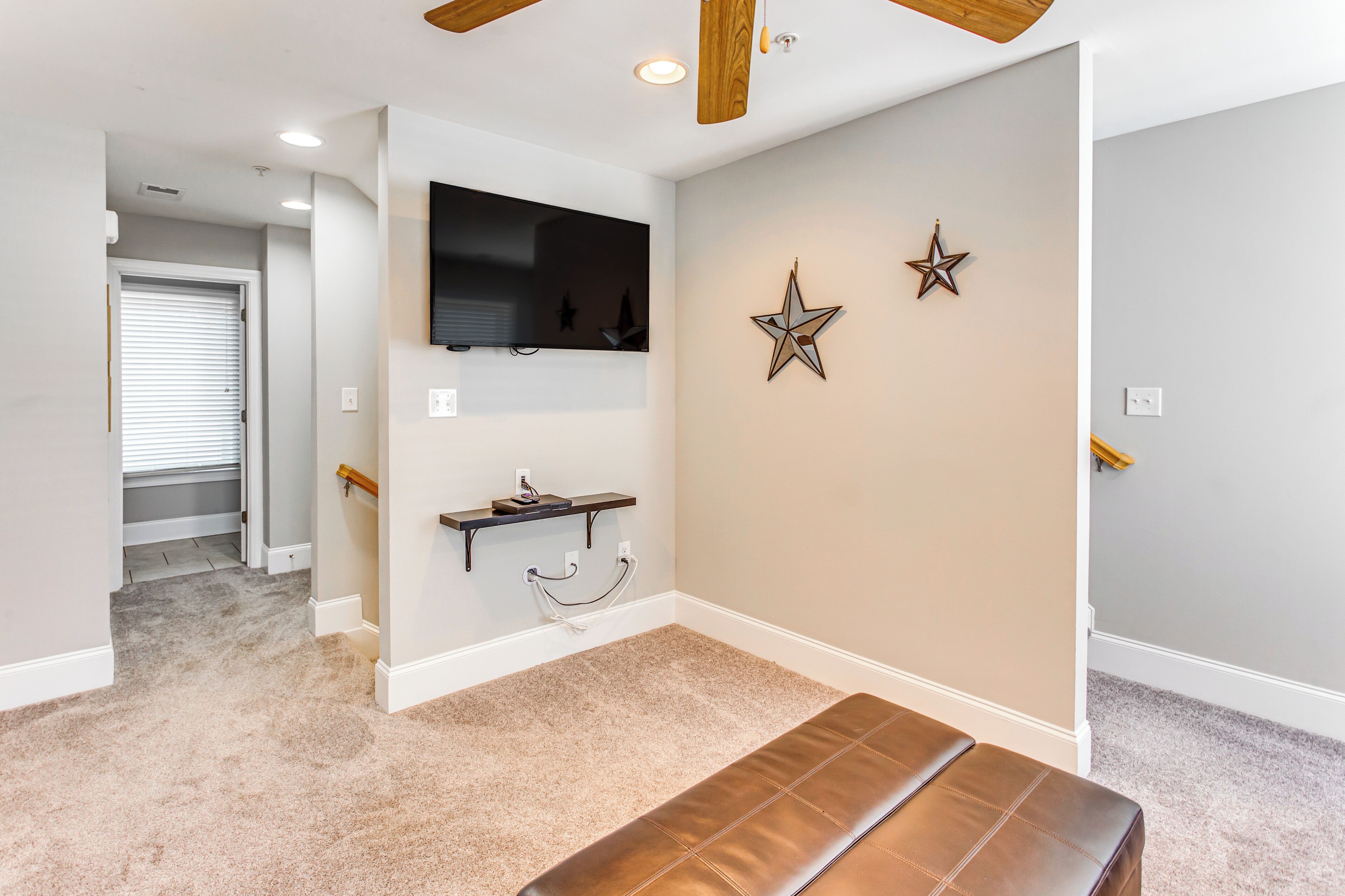 Un salon moderne avec un grand téléviseur à écran plat fixé au mur, un banc et deux décorations en forme d’étoile.