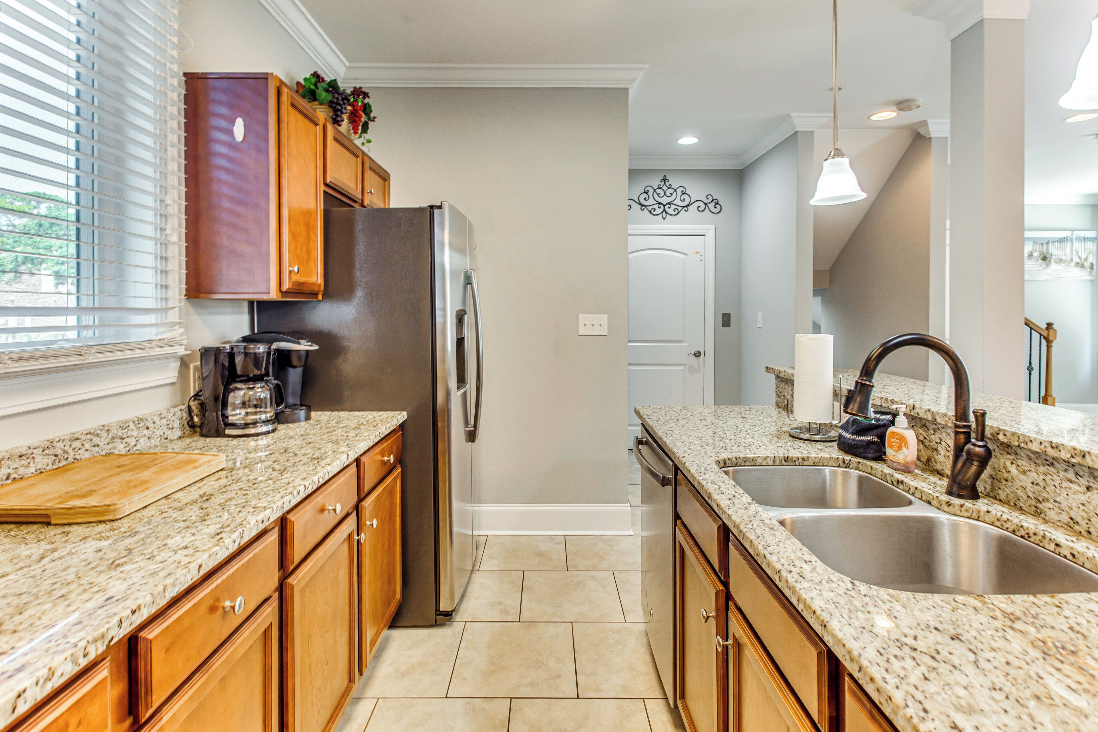 A kitchen with granite countertops, wooden cabinets, stainless steel appliances, and a double sink.