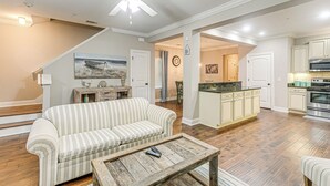 Un salon spacieux avec un canapé à rayures, une table basse en bois et un ventilateur de plafond.