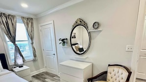 Une chambre à coucher avec un lit, une commode, une chaise et un miroir au mur.