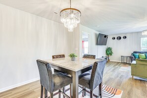 A dining area with a marble table and chairs, a chandelier, and a living room with a sofa and a TV. - Mod Triana Home 7 Mi to Huntsville Int'l Airport (Madison)