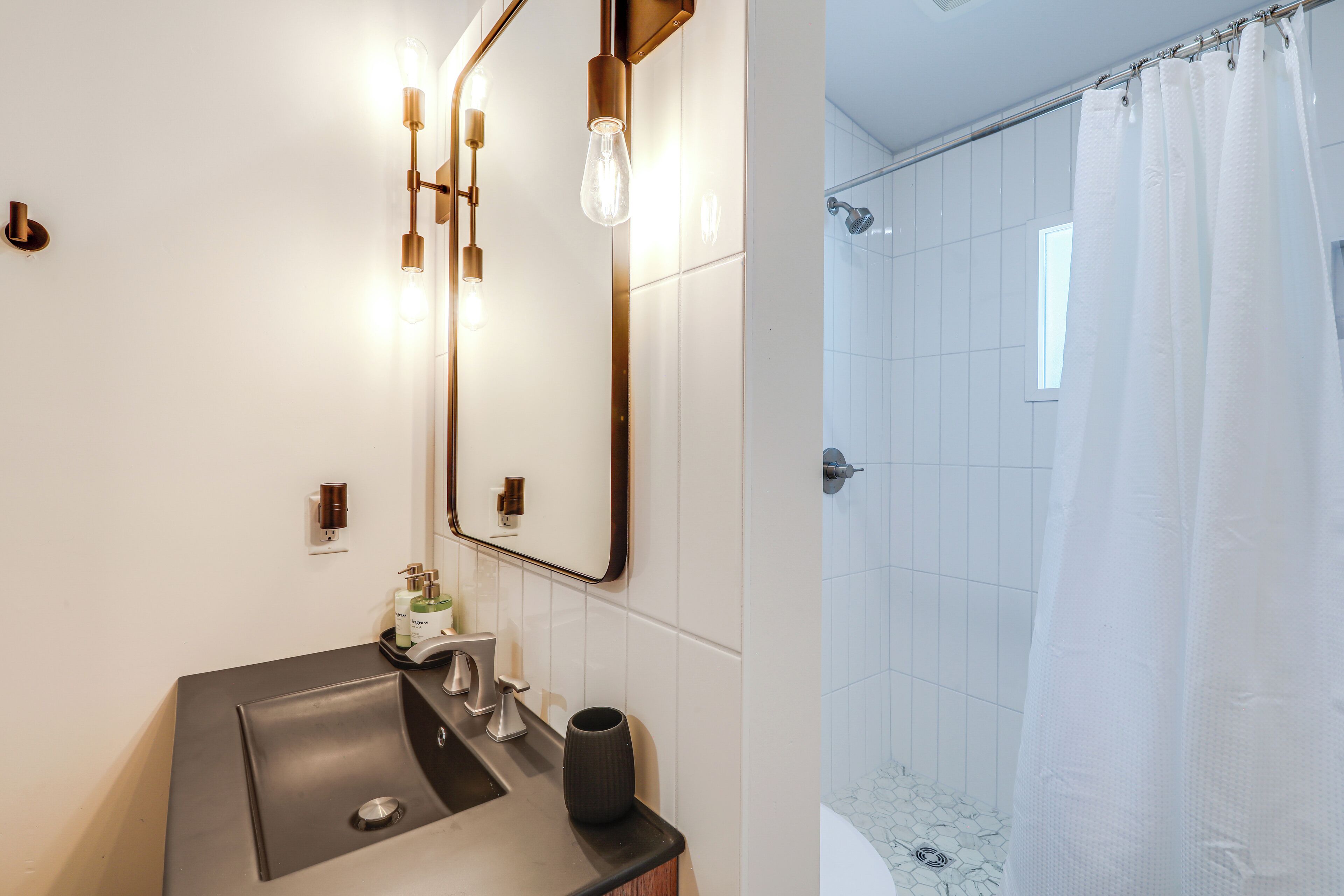 Ein modernes Badezimmer mit großem Spiegel, Waschbecken und Duschbereich.