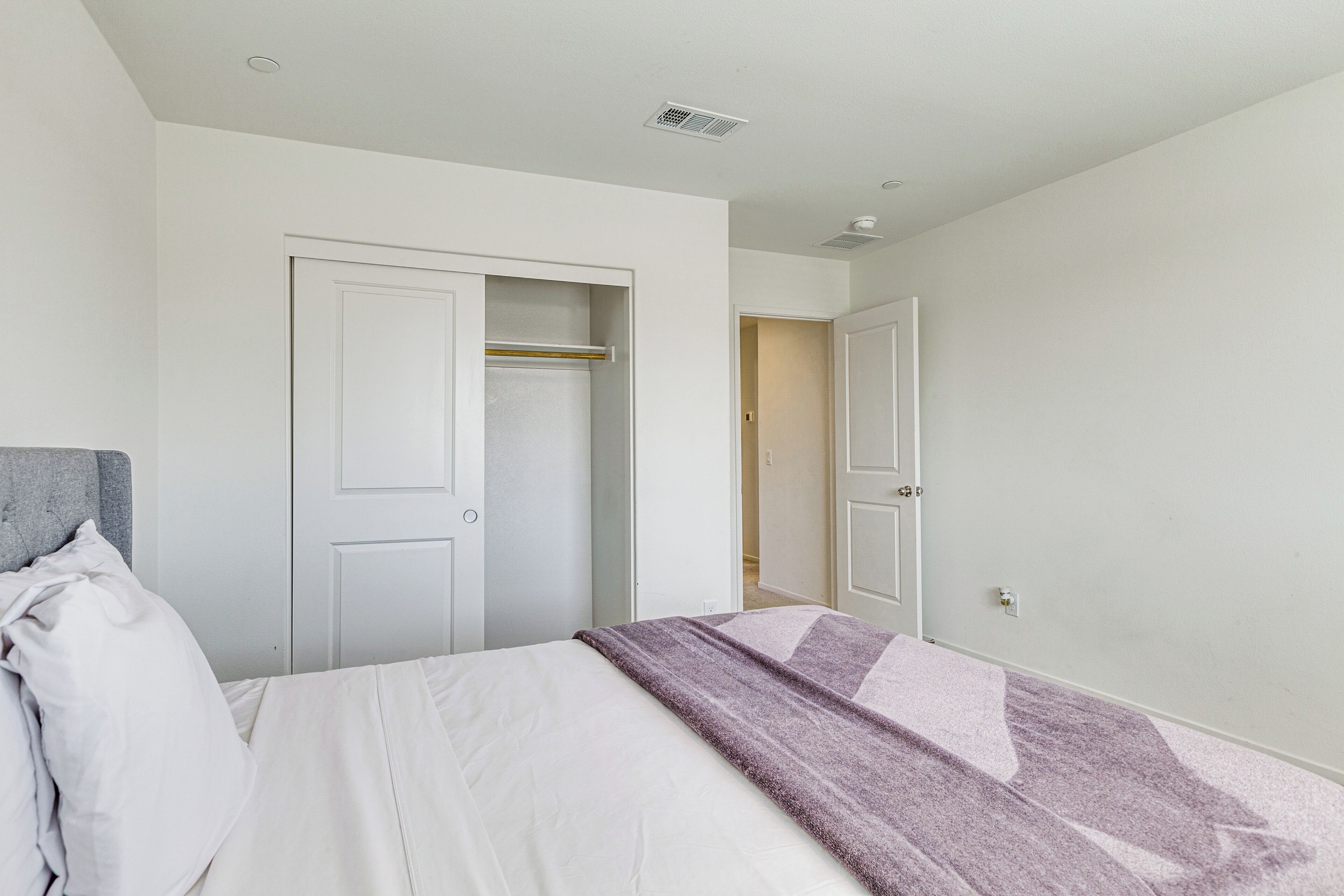 A bedroom with a bed, a wardrobe, and a door leading to another room.