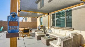 Eine Terrasse im Freien mit Korbmöbeln, einem Grill und einem überdachten Sitzbereich.